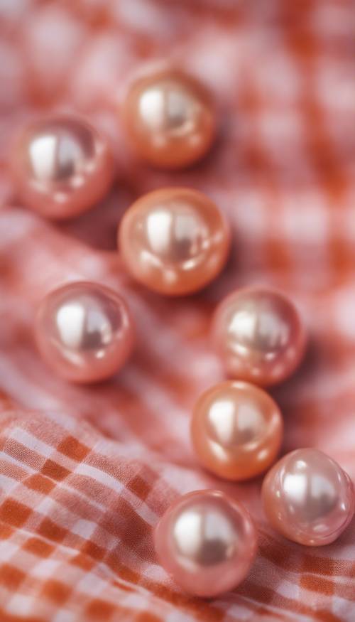 Primo piano di perle rosa vintage, adagiate su un classico tessuto scozzese arancione in stile preppy.