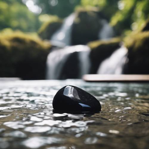 Une pierre noire et lisse posée dans le bassin peu profond d’une cascade rugissante.