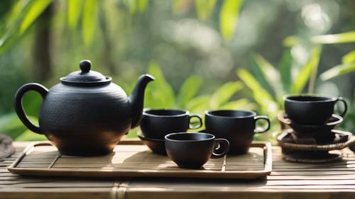 Schwarzes Teeservice aus Holz im asiatischen Stil, auf einem Bambustisch im Freien.