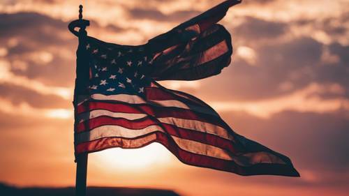 Wielokolorowy zachód słońca z sylwetką amerykańskiej flagi na czele.