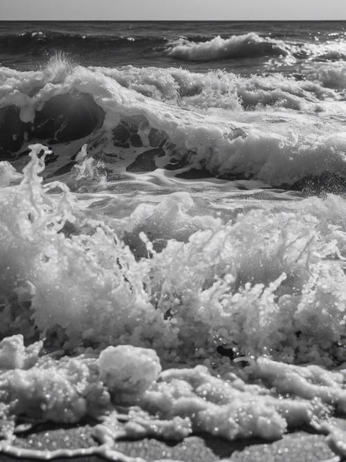 Черно-белое изображение серых пенистых морских волн, бьющихся о берег.