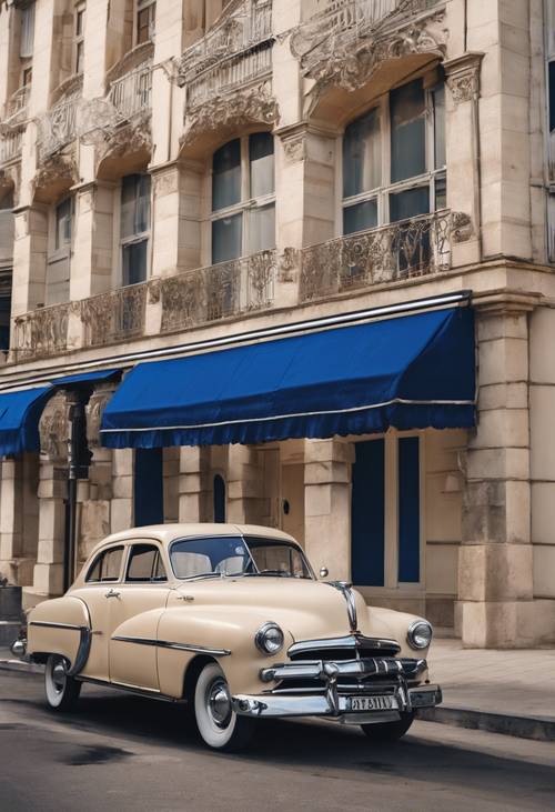 سيارة باللون البيج تعود إلى الخمسينيات متوقفة أمام مبنى أزرق ملكي.