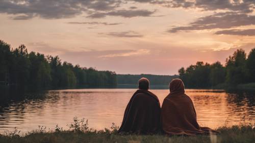 A couple nestled up in a blanket, watching a September sunset over a lake ផ្ទាំង​រូបភាព [98e67aed87464404beae]