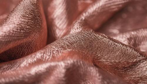 Un primo piano di un tessuto in filo metallico oro rosa.