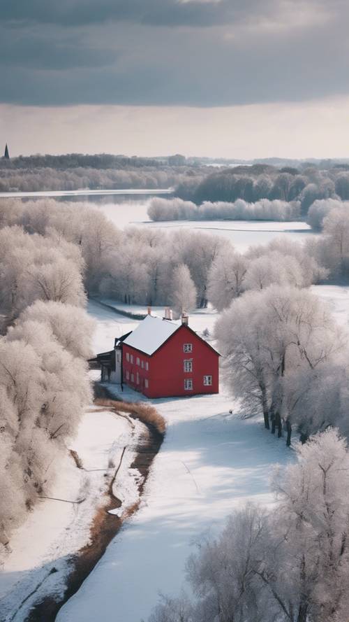 白雪覆蓋的法國鄉村風景，光禿禿的樹木，冰凍的河流，遠處還有一棟紅頂小房子。
