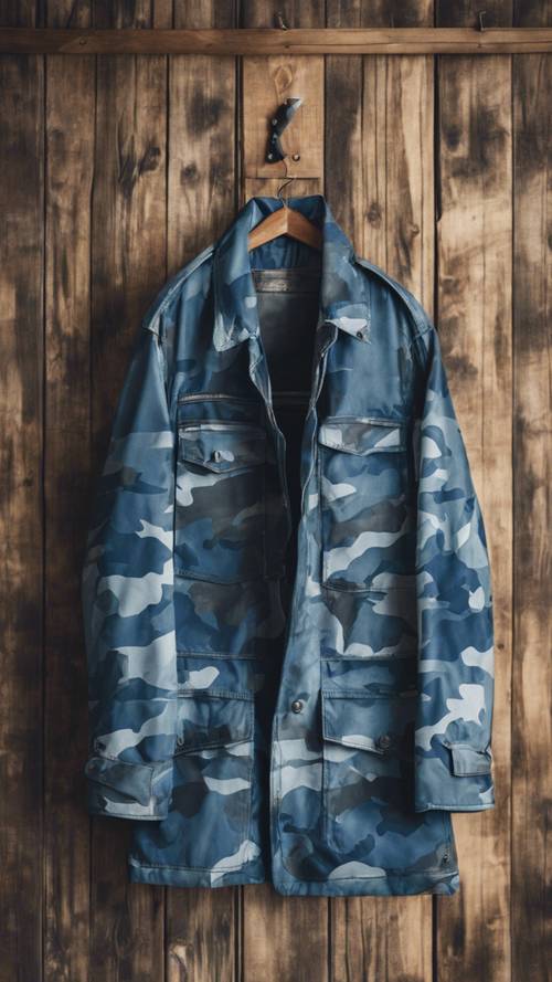 Vintage niebieska kurtka wojskowa w kamuflażu wisząca na drewnianym wieszaku.