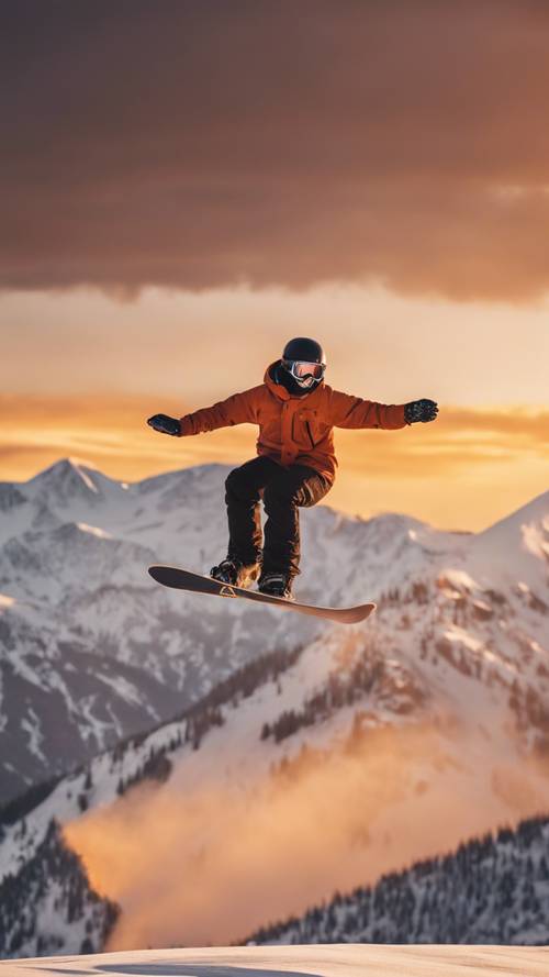 A snowboarder catching air off a jump in front of a snowy mountain range bathed in orange glow of a sunset.