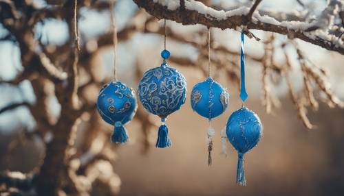 A cluster of handmade blue boho ornaments hanging from a tree.