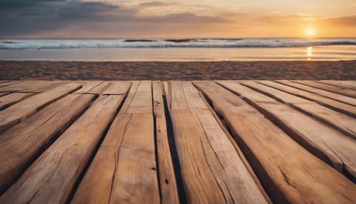 Brown wooden deck overlooking an empty beach during sunset.