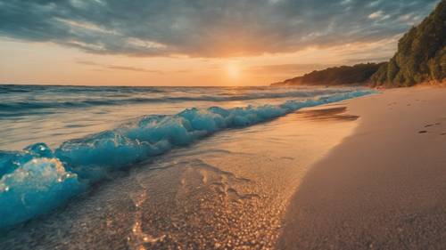Ondas azuis azuis com reflexos laranja de um pôr do sol de verão contornando uma praia arenosa.