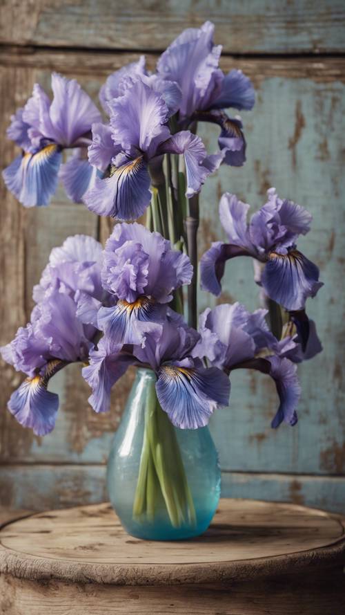 Iris azules en un jarrón rosa vintage sobre una mesa rústica de madera.