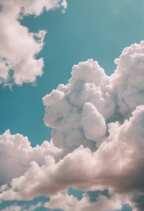 Beżowe chmury przypominające miękką watę cukrową unoszące się na lazurowym niebie.
