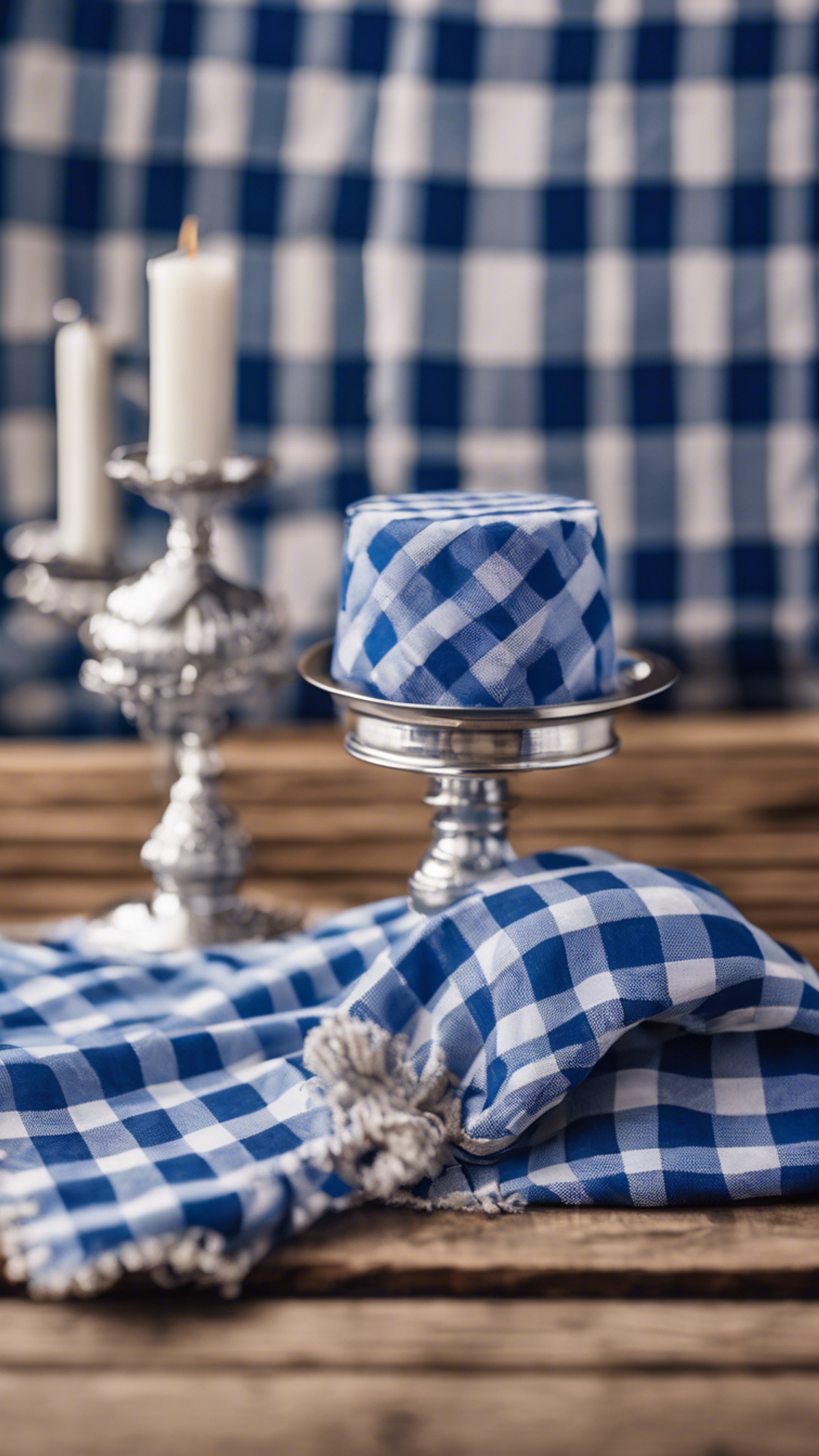 Classic blue checkered gingham fabric draped over a wooden table with a silver candelabra, evoking a preppy picnic scene. Tapeta[5483729deeeb4e2a9f91]