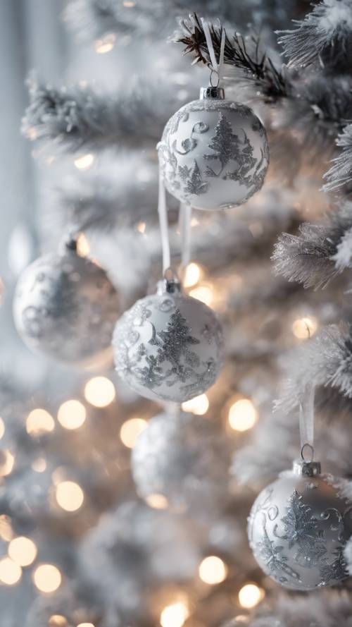Décorations de Noël blanches et argentées accrochées à un arbre enneigé.