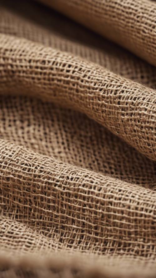 天然棕褐色粗麻布织物的特写，显示其粗糙且开放的编织。