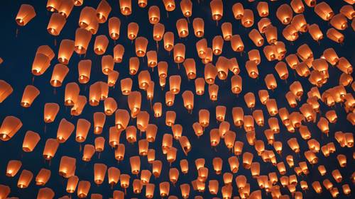 View of a night sky filled with multiple flying lanterns let off during Diwali celebration.