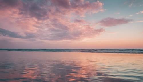 Un magico cielo color pastello che si riflette su un mare calmo durante il tramonto.