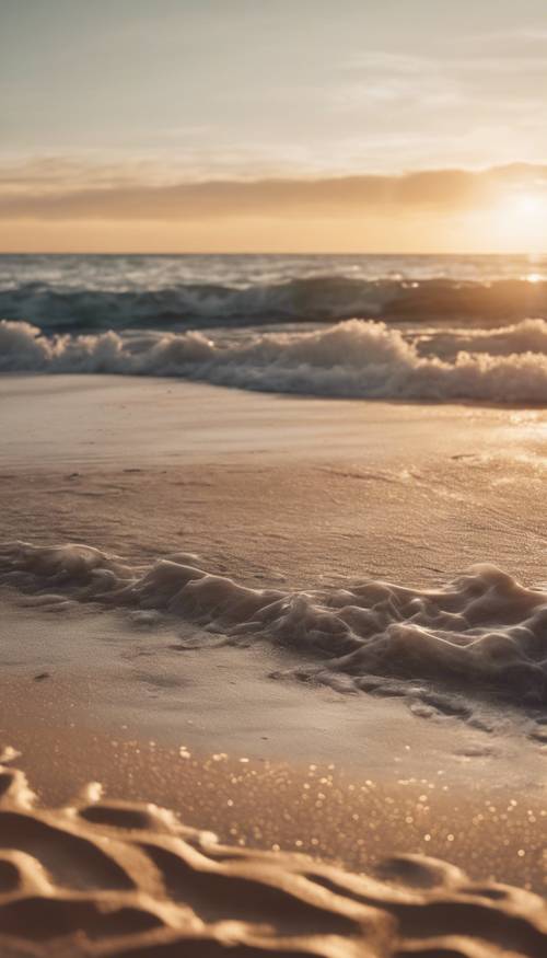مشهد شاطئ هادئ مع الرمال البيج وغروب الشمس والمحيط المتموج الناعم.