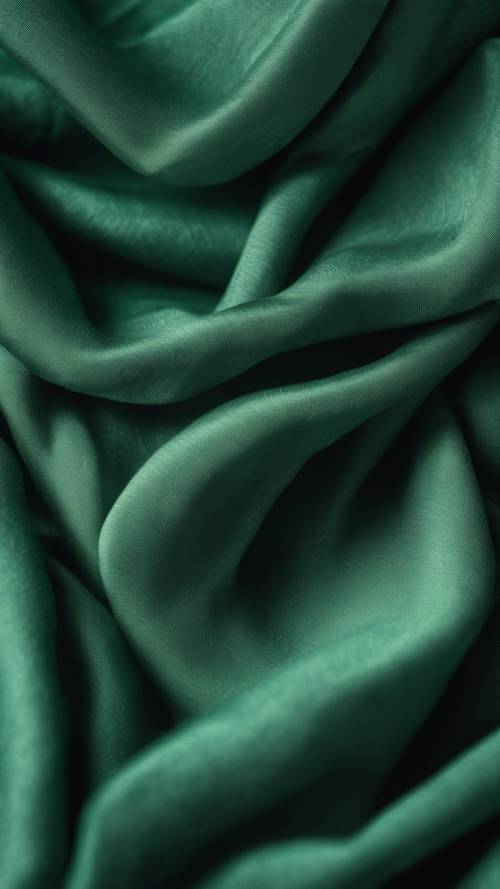 Dramatically lit emerald linen fabric amidst shadowy folds and smooth surfaces.