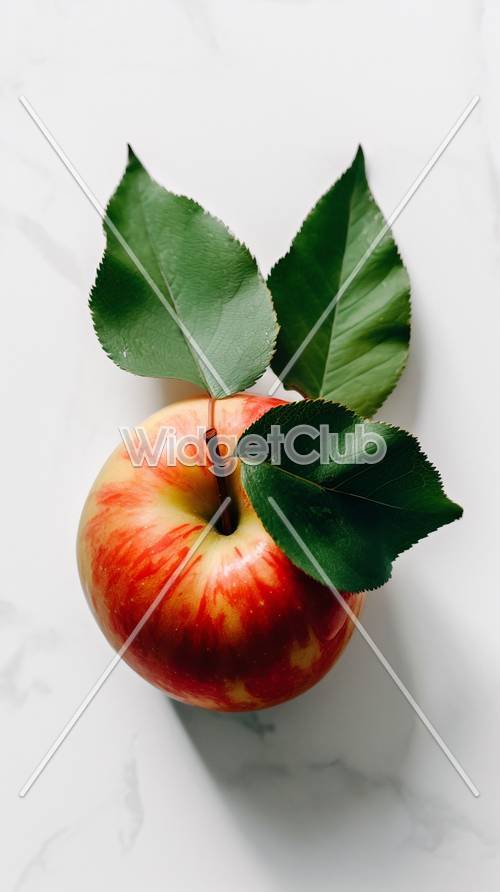 Kolorowe jabłko z zielonymi liśćmi
