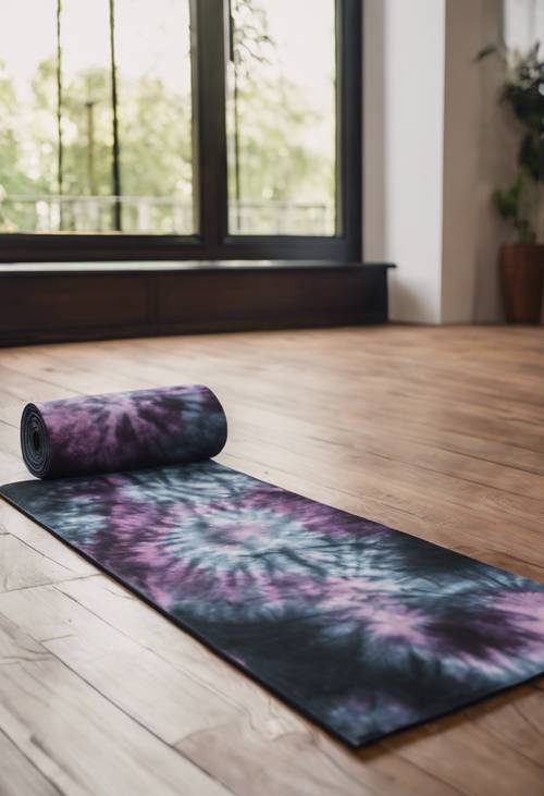 A black tie dye yoga mat on a wooden floor.