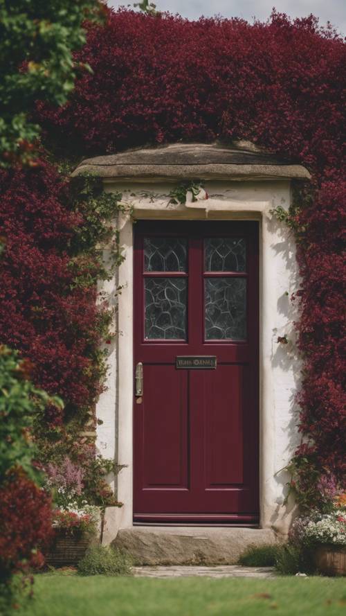 A burgundy door of a postcard-perfect cottage in the English countryside's picturesque scenery.