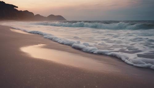 Pemandangan pantai yang menenangkan saat senja dengan ombak lembut bercahaya menyapu pantai dengan indah secara estetika.