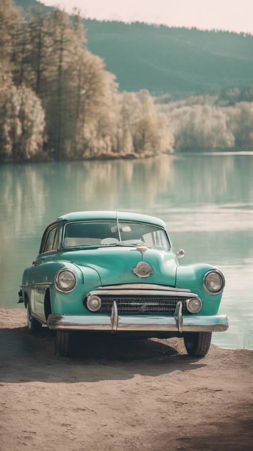 An old, vintage car in cool pastel teal, parked by a beautiful lake.