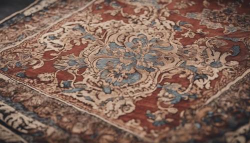 A detailed view of a worn-out antique damask rug with intricate arabesque patterns.