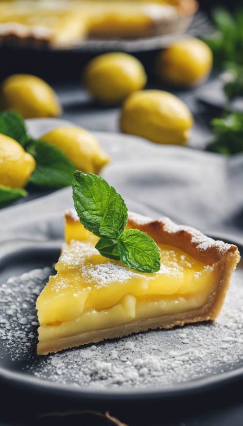 A close-up of a zesty lemon tart garnished with mint leaves and icing sugar.