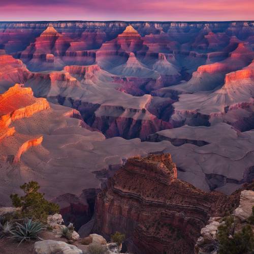 A panoramic view of the Grand Canyon at sunset with all hues of orange, indigo and purple