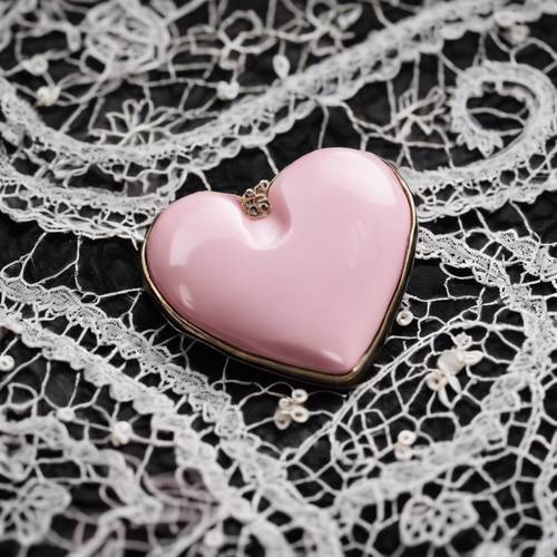 A vintage pink heart brooch on a black lace fabric.