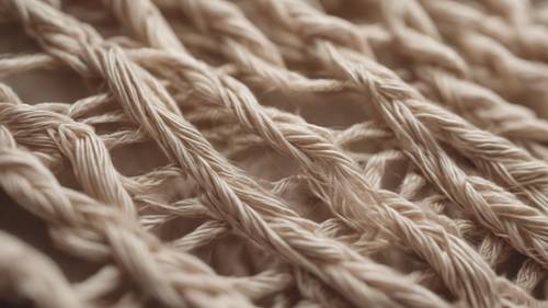 Zbliżenie chłodnych beżowych nici przeplatających się, tworząc niepowtarzalną, wzorzystą tkaninę.