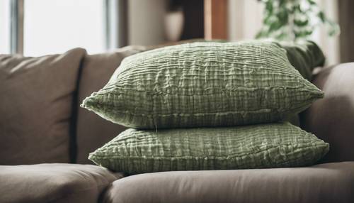 Una pila di cuscini testurizzati verde salvia su un accogliente divano del soggiorno.