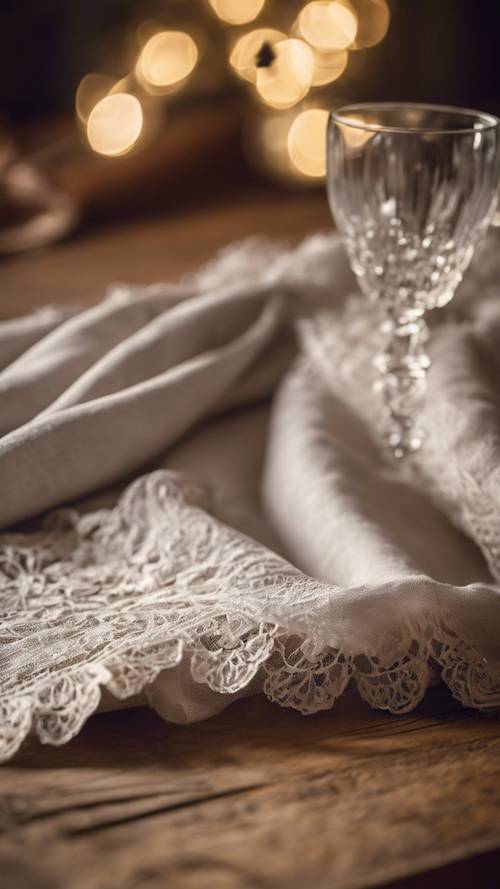 A softly lit linen tablecloth with an antique lace trim draped over a rustic wooden table.