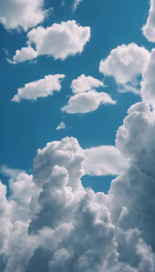 Trzy puszyste białe chmury w kształcie zwierząt na szafirowoniebieskim popołudniowym niebie.