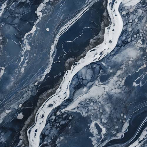 An aerial shot of a dark blue marble surface, its white veins resembling crashing ocean waves.