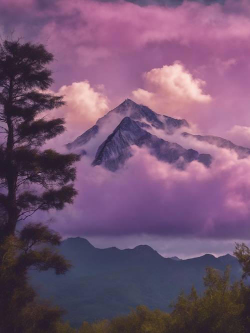 Un sommet de montagne solitaire touchant les nuages ​​violets bas au petit matin.