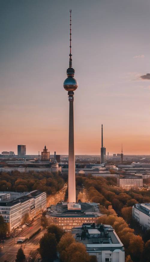 Gambaran umum kota Berlin saat matahari terbenam di sore hari yang cerah, dengan Menara Televisi Berlin yang ikonik berdiri tegak dan megah di tengah lanskap kota.