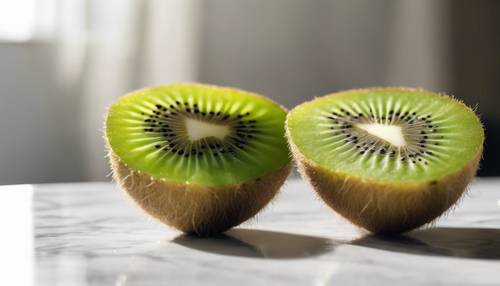 Two halves of a kiwi fruit on a white marble table with morning sunshine.
