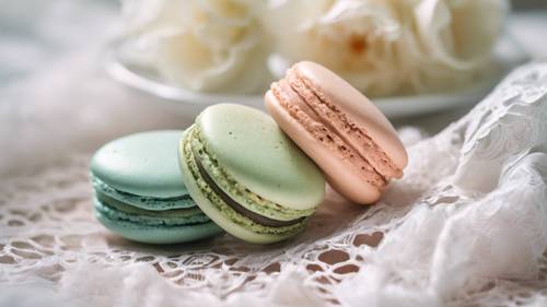 Un trío de macarons en suaves colores pastel dispuestos sobre un mantel de encaje blanco, creando una estética delicada.