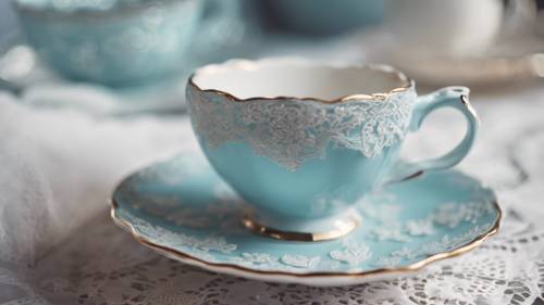 An ornate pastel blue teacup and saucer set on a lace tablecloth.