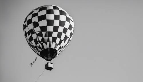 Balon na ogrzane powietrze w czarno-białą kratkę unoszący się na czystym, błękitnym niebie.