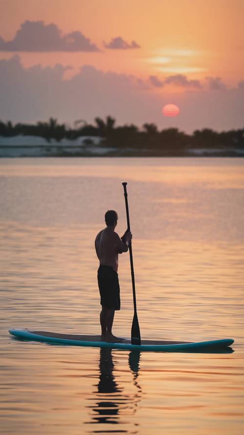 日出時，在比斯坎灣平靜的水面上，槳板衝浪者的寧靜景象。