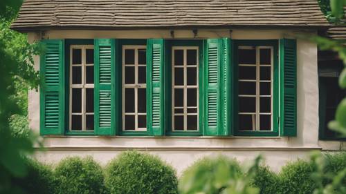 บานประตูหน้าต่างสีเขียวแบบเก่าโดยมีฉากหลังเป็นบ้านในชนบทที่มีเสน่ห์แบบโบราณ