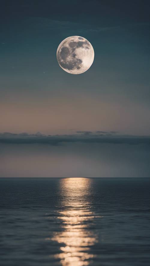 Uma lua cheia iluminando um oceano calmo durante a noite.