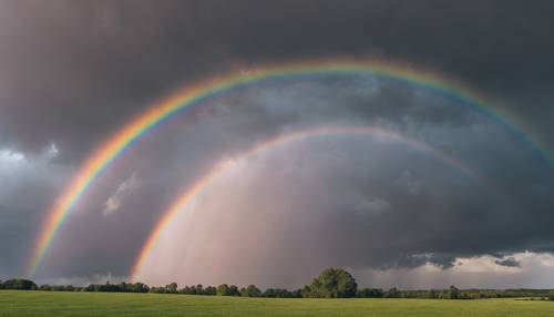 Um arco-íris pastel formando um arco em um céu tempestuoso em tons de cinza proporcionando um contraste.