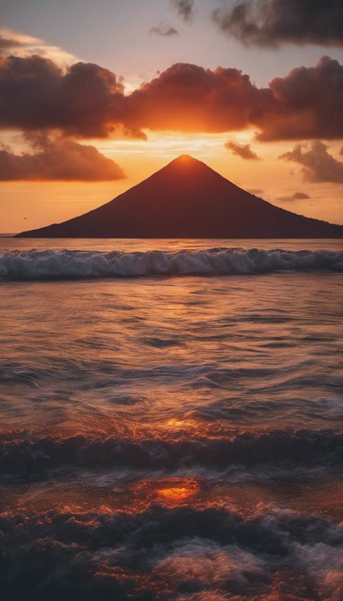 Ein tropischer Sonnenuntergang, bei dem die Sonne hinter einem Vulkan versinkt.
