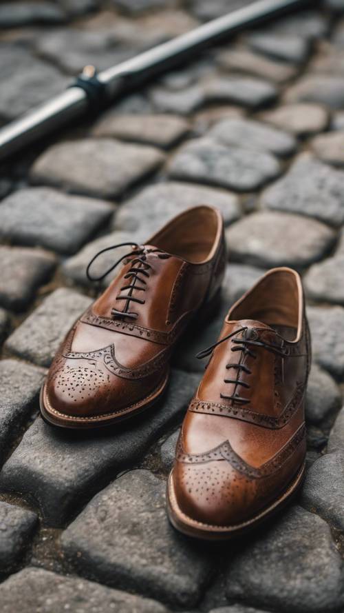 A pair of detailed, handcrafted leather oxford men's shoes on a cobblestone road in London.