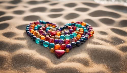 A heart made of vibrant boho beads, nestled in the sand with ocean waves lapping at it.